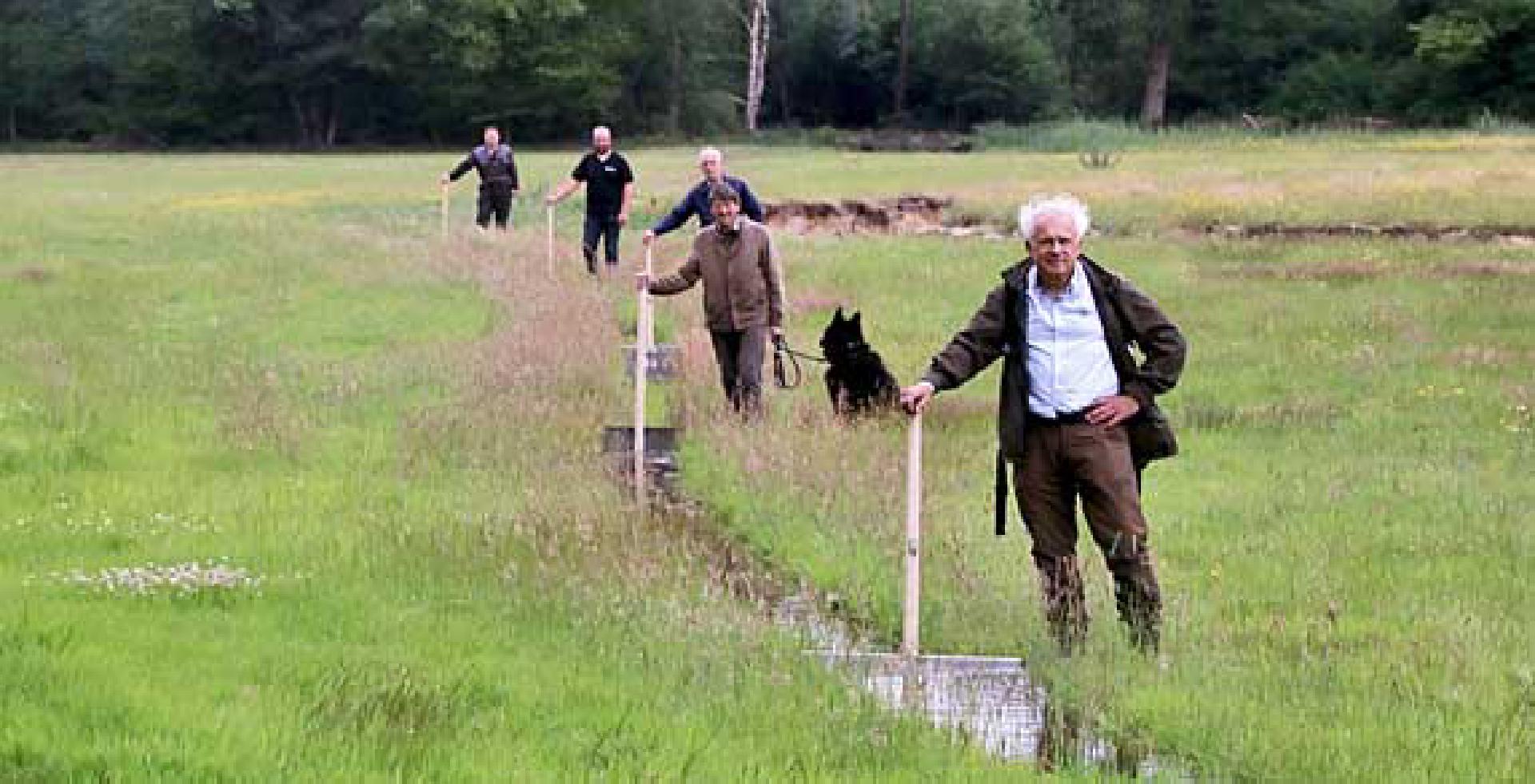 Foto van het vloeiweiden team met kroeven in de watergeul. Eric Brinckmann staat voorop.